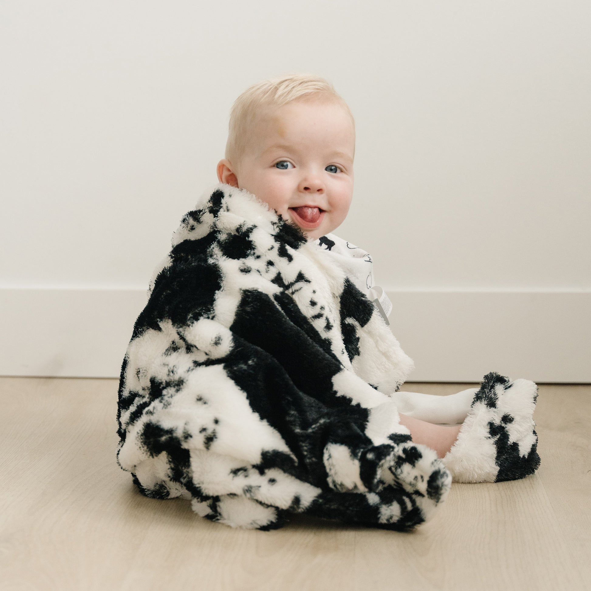  Cow Print Plush Baby Blanket ; stylized room image with model
