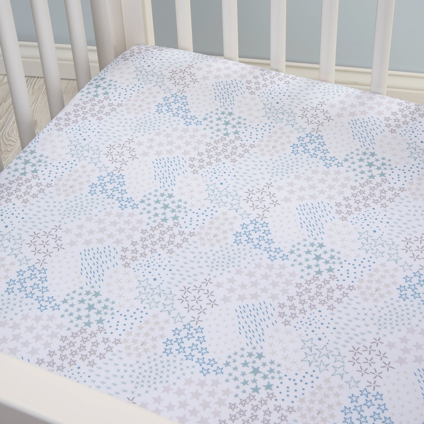 Trend Lab Starry Night Fitted Crib Sheet stylized on a crib mattress in a white crib, picture taken at an corner angle view.