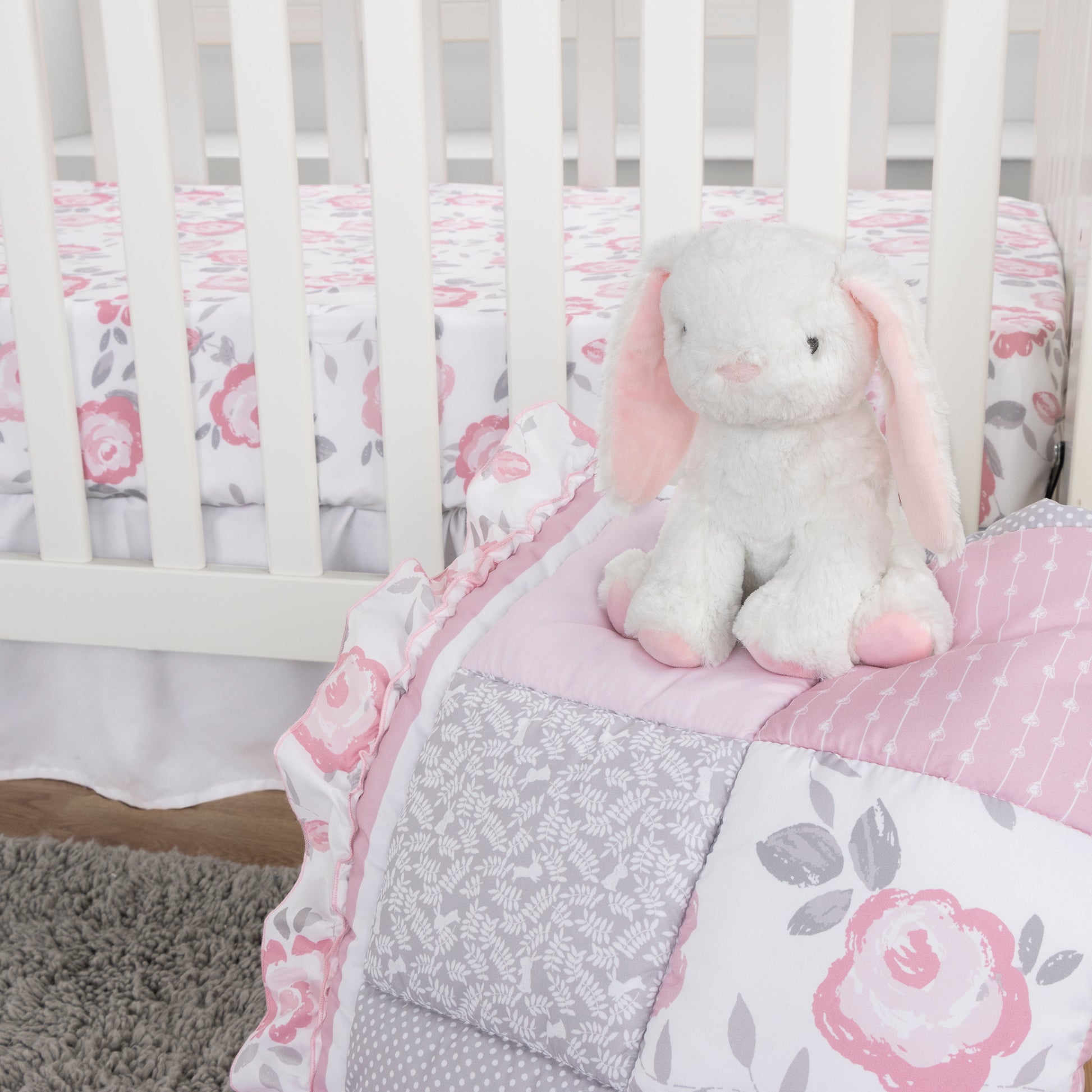 Emma 4 Piece Crib Bedding Collection by Sammy and Lou; stylized nursery image featuring adorable bunny plush and beautiful nursery quilt, crib sheet and crib skirt