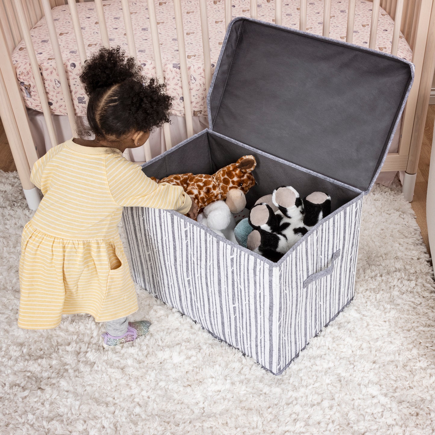 Birch Felt Toy Box by Sammy & Lou® with lid open with toys and stuffed inside and little girl reaching in