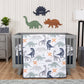 Prehistoric Dino’s 3 Piece Crib Bedding Set in stylized bedroom. The nursery quilt, fitted crib sheet, and skirt sit on a gray crib on the middle of hte room. A gray dresser, plant and storage caddy sit on the left side, and a tall standing lamp with a felt hamper sit on the right. Dino wooden decor sits hangs on the back wall with a gray rug on the floor and a natural wooden floor.
