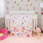 Floral Sprinkles 4 Piece Crib Bedding Set by Sammy & Lou® - stylized in a bedroom. The quilt, crib sheet and skirt on a white crib with the lady bug plush toy in front of the crib on a wooden stool.  On the right sits a toddler plush flower chair, on the right sits a white dresser with accessories on it. The walls surrounding is floral wallpaper.