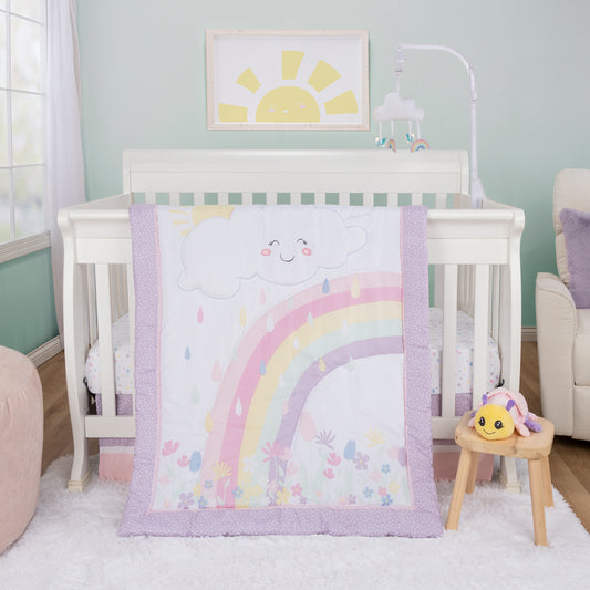 Rainbow Showers 4 Piece Bedding Set by Sammy & Lou® in stylized bedroom. The nursery quilt, fitted crib sheet, and skirt sits on a white crib with the plush in front of the crib on a birch stool, with a white rug and natural flooring below it.  A pink Loufa sits to the left of the crib, a white chair sits to the right of the crib, and a sun wall decor hangs behind the crib. A pastel butterfly and rainbow muscial crib baby mobile hang above the crib (and is sold separately)